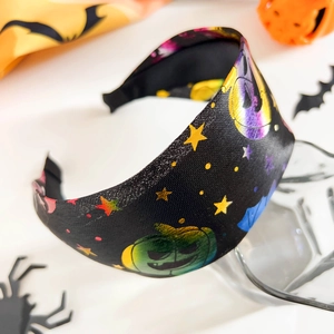 Détail d'un serre-tête noir d'Halloween avec motifs de citrouilles et d'étoiles