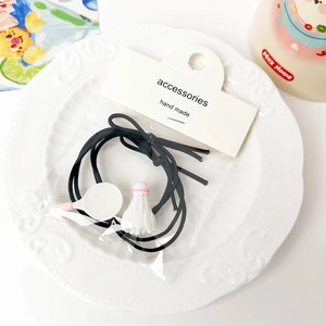 Close-up of badminton racket and shuttlecock charms on black elastic hair ties