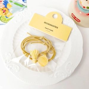 Macro detail of yellow badminton racket hair ties on an embossed white ceramic plate