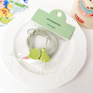 Close-up of cute badminton racket and shuttlecock hair tie set in a ceramic tray