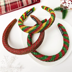 Close-up of three handmade Christmas glitter headbands with festive stripe patterns and label