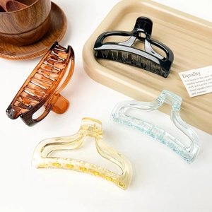 Detailed view of amber and pastel shark hair claws on a minimalist lifestyle tray