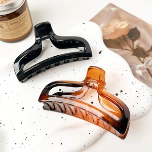Elegant amber and black fish tail hair claws on a white marble display with a candle