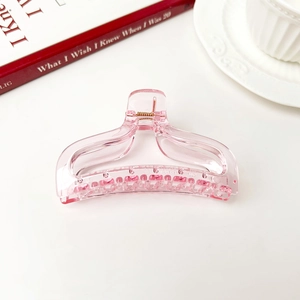 Close-up of pink transparent resin fishtail hair claw clip with metal spring detail