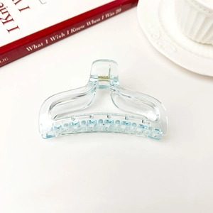 Detail view of the transparent light blue fishtail hair claw with golden metal spring