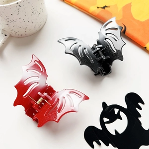Close-up of black and red bat-shaped hair claws with hollow wings for Halloween