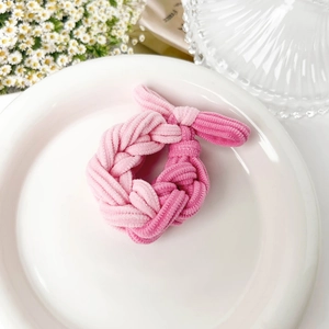 Close-up of pink braided cord hair tie showing ribbed velvet texture and woven design