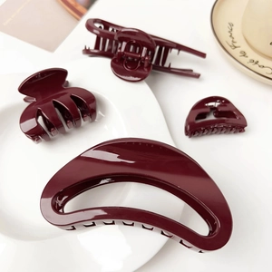 Detailed set of four burgundy hair claws in various sizes on a minimalist white tray