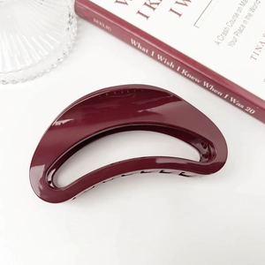 Detail view of glossy dark burgundy hair claw clip with smooth curved design