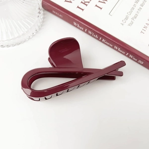 Detailed close-up of dark red hair claw clip with glossy finish on a minimalist background