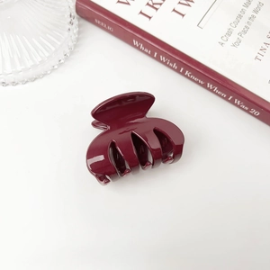 Glossy deep red hair claw clip on book background with elegant resin mirror finish
