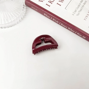 Macro shot of minimalist burgundy red hair claw clip with glossy geometric hollow design