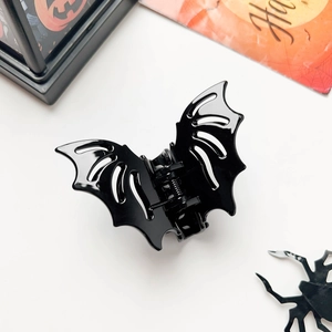 Detail shot of black bat-shaped hair claw clip with spider and pumpkin holiday props