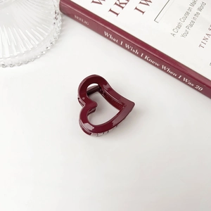 Close-up of a minimalist burgundy heart-shaped claw clip with a glossy resin finish