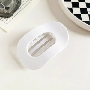 Nahaufnahme einer weißen ovalen Haarklammer mit hohlem Design im minimalistischen Stil