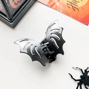 Close-up of black matte bat hair claw with glitter details for Halloween hair styling