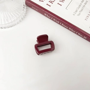 Detail of elegant deep red acrylic hair claw clip with glossy finish and hollow design