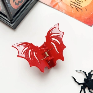 Detailed close-up of a red bat hair claw clip with golden metal spring for Halloween