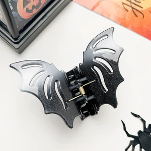Detail shot of a black bat-shaped hair claw with glitter finish for Halloween parties