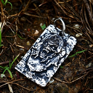 Macro shot of vintage skull vampire pendant in blacked stainless steel on natural ground