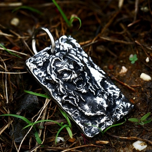 Detailed close-up of a vintage skull pendant with deep relief on a natural outdoor background