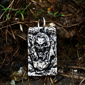 Macro detail of a gothic beast face pendant with aged silver finish in outdoor setting