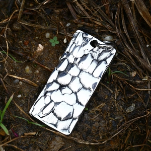 Macro shot of a rectangular stainless steel pendant with rustic hammered texture finish