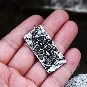 Macro view of vintage stainless steel skull pendant with floral details held by hand