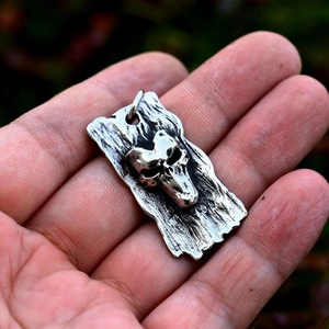 Macro shot of a vintage silver skull pendant showing rugged metallic texture and details