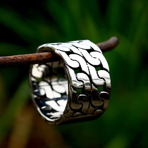 Men's silver stainless steel Cuban link chain ring displayed on a natural branch