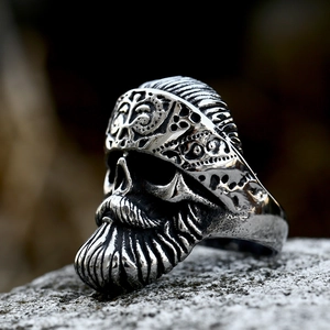 Vintage stainless steel skull ring with detailed beard and headband on a rock