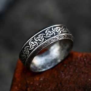 Vintage stainless steel ring with Celtic knot carvings on a rustic industrial surface