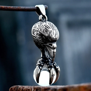 Macro shot of stainless steel eagle claw holding a clear glass ball on vintage stone
