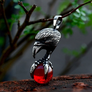Detailed view of stainless steel eagle claw pendant with red gemstone on a branch