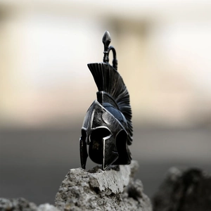 Macro shot of retro Spartan helmet pendant with detailed plume on a textured stone surface