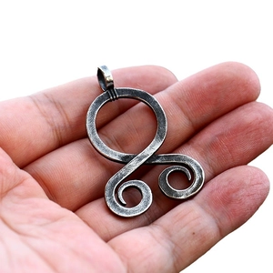Vintage stainless steel octopus pendant in Viking style held in hand on white background