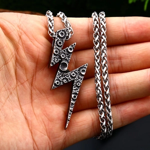 Macro detail of lightning bolt pendant with crater texture and chunky woven chain