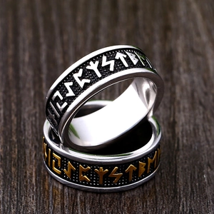 Viking rune rings in stainless steel with vintage engravings on dark wood background