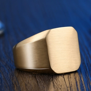 Macro shot of minimalist gold signet ring with brushed matte finish on a dark wood surface