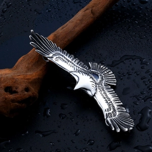 Vintage stainless steel eagle pendant with detailed feather carving on wood background