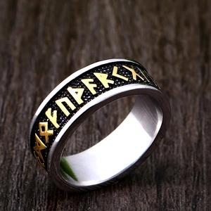 Viking rune ring in stainless steel with gold runes on a dark textured background