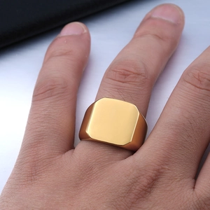 Close-up of a polished gold-plated square signet ring worn on a finger for men