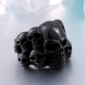 Détail d'une bague en acier noir de style punk avec motifs de crânes superposés