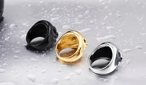 Detailed macro view of three skull rings in black, gold, and silver finishes on water surface