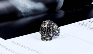 Détail macro d'une bague tête de mort gothique avec croix dorée et gravures fines