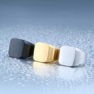 Three men's matte brushed signet rings in black, gold and silver on a blue water mirror