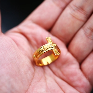Polished gold stainless steel ring with detailed crucifix relief on a man's palm