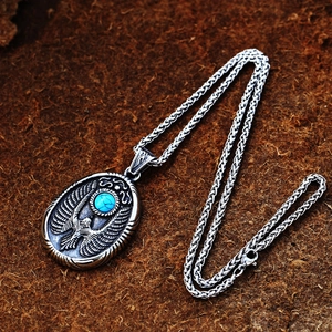 Makroaufnahme von Retro-Adler-Anhänger mit Türkis-Inlay und strukturierter Silberkette