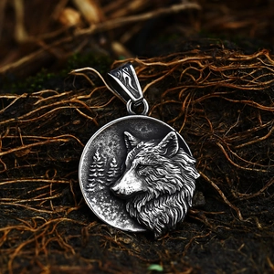 Macro shot of vintage stainless steel wolf head round pendant on natural mud background