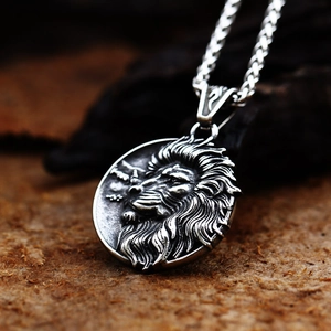 Macro detail of silver stainless steel lion head relief on a vintage round pendant